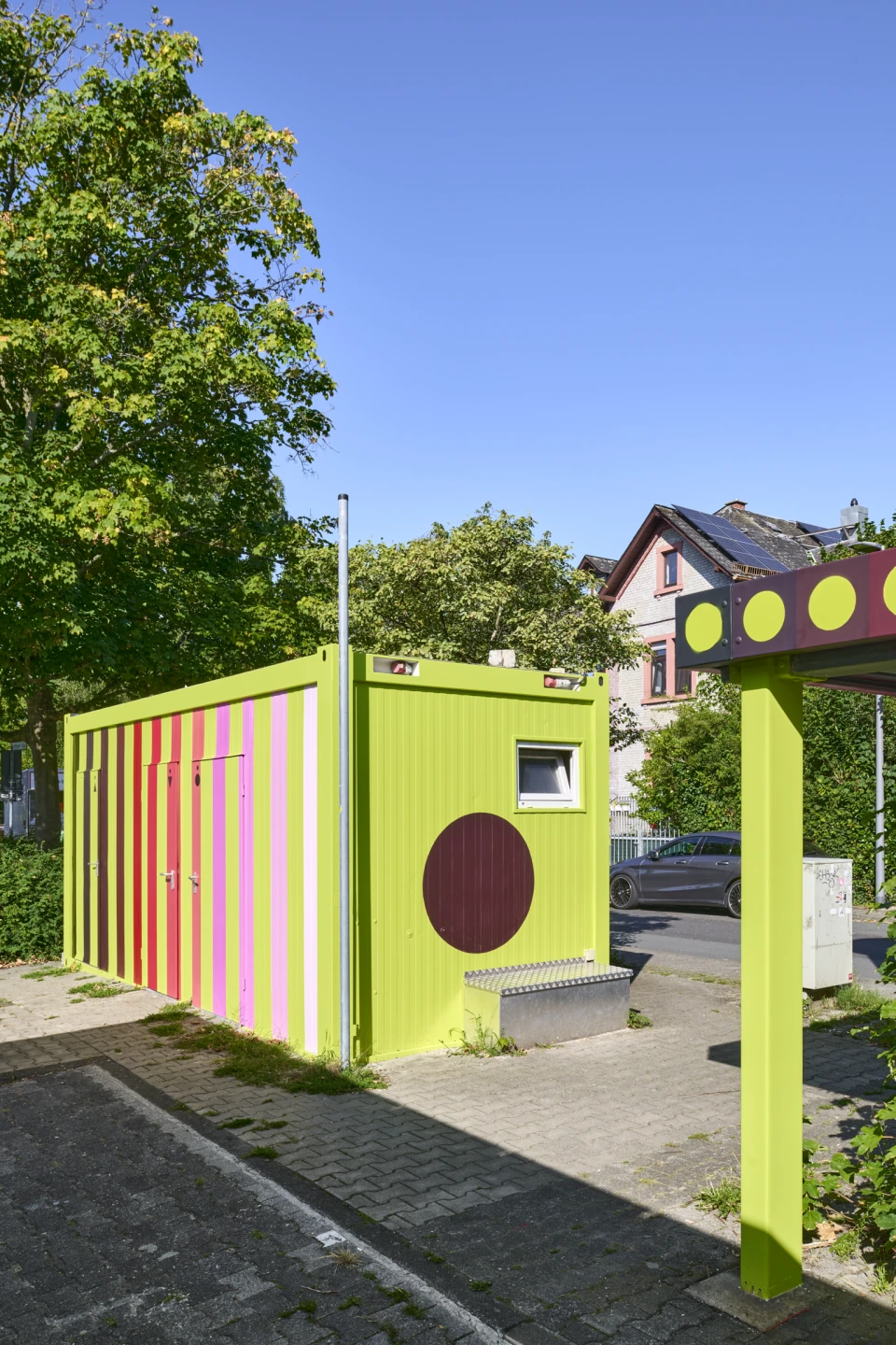 Lackierter Toilettencontainer mit Fahrradunterstand im Anschnitt